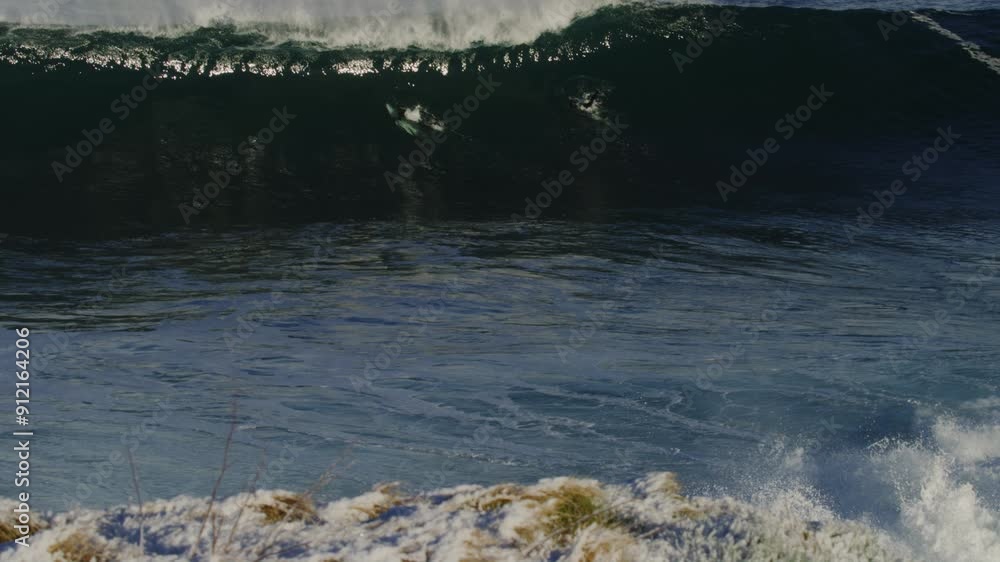Poster powerful wave swallows up surfers in wetsuits exploding into whitewash, slow motion viewed from abov