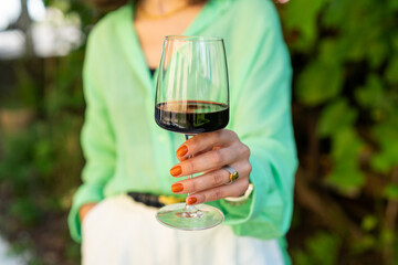 Stylish woman rising glass with red wine