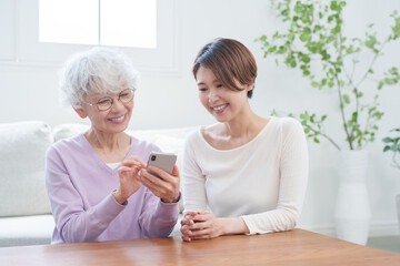 高齢者の母親にスマホを教える娘（家族・ファミリー）