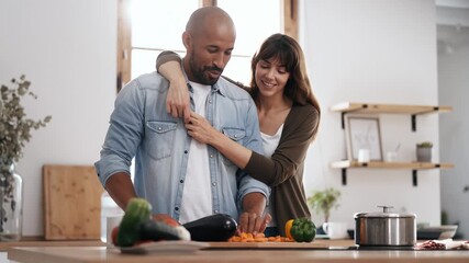 Video of beautiful and romantic couple hugging while cutting vegetables in the kitchen at home - Powered by Adobe