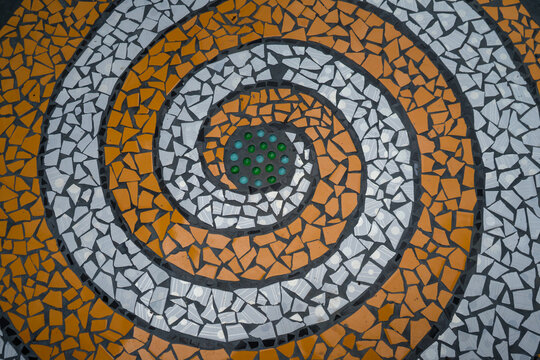 Broken colorful tiles mosaic made from leftover tile scraps to recycle for decorated on the floor or wall to spiral or circle look like Mosaic tiles .
