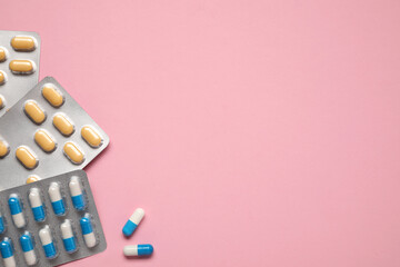 Different antibiotic pills in blisters on pink background, flat lay. Space for text