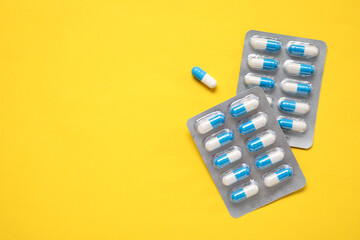 Antibiotic pills in blisters on yellow background, top view. Space for text