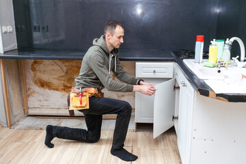 Older man disassembling apartment kitchen out of service