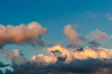 Dramatic clouds in the blue sky in the morning, the rising sun rays hitting the clouds