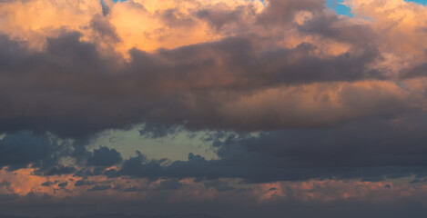 Dramatic clouds in the blue sky in the morning, the rising sun rays hitting the clouds