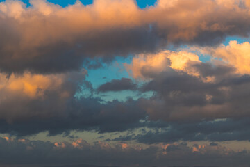 Dramatic clouds in the blue sky in the morning, the rising sun rays hitting the clouds