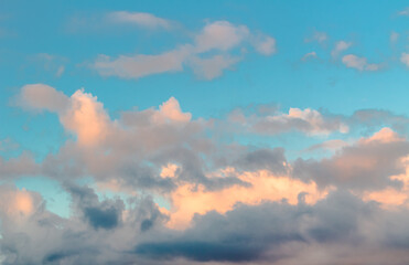 Dramatic clouds in the blue sky in the morning, the rising sun rays hitting the clouds