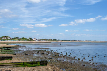 deserted beach at Hill Head Meon Shore Hampshire England with beach huts and blue sky in the background