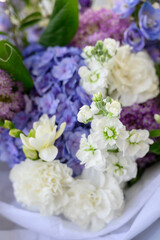 a beautiful freshly cut bouquet of mixed flowers. Bouquet of fresh hydrangeas, freesia, carnations, Allium Flowers in blue and pastel colors