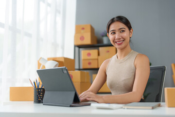 Obraz premium Start up small business entrepreneur SME or freelance asian woman using laptop with box, Young success Asian woman with her hand lift up , online marketing packaging box and delivery, SME concept.