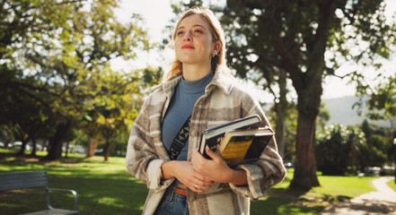 Student, woman and books in park for walk to class with education, learning or thinking for...