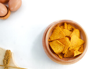 Corn chips on wooden plate isolated on white background. Crispy snack dessert. Food Photography Concept
