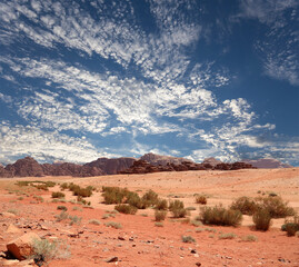 Wadi Rum Desert also known as The Valley of the Moon (against the sky with clouds)-- is a valley cut into the sandstone and granite rock in southern Jordan 60 km to the east of Aqaba