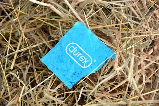 Kielce, Świętokrzyskie, Poland - 2022-07-28 - The empty condom wrapper Durex is lying on the hay