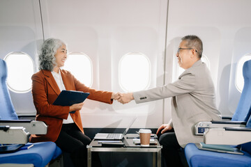 Business meeting in airplane, asian Mature businessman in private jet is talking with Mature female colleague and documents, business people flying in airplane