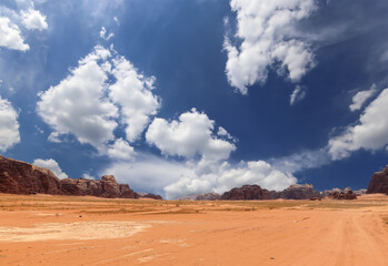 Wadi Rum Desert also known as The Valley of the Moon (against the sky with clouds)-- is a valley cut into the sandstone and granite rock in southern Jordan 60 km to the east of Aqaba