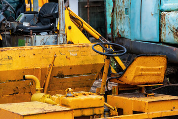 A close-up shot of the yellow rusty cab of a construction excavator. Heavy construction industry equipment