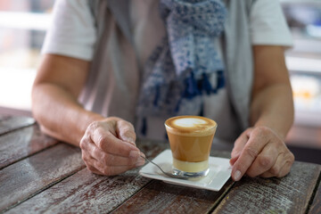 Close up on senior woman's hands ready to drink a hot coffee and milk beverage