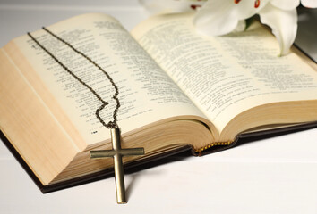 Fototapeta premium Cross with chain and Bible on white wooden table, closeup. Religion of Christianity