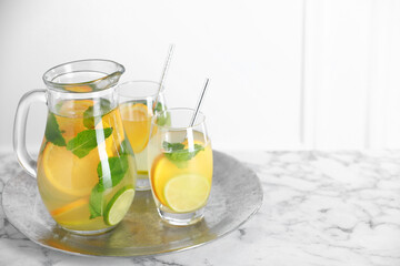 Freshly made lemonade with mint in jug and glasses on white marble table