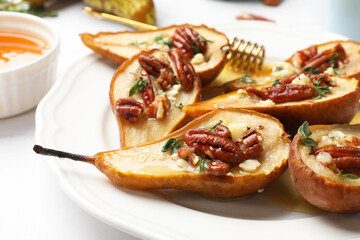 Delicious baked pears with nuts, blue cheese, thyme and honey on white table, closeup