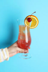 Woman with glass of refreshing cocktail on light blue background, closeup