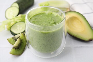 Delicious green smoothie and ingredients on white table, closeup