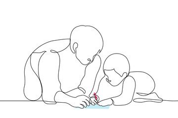 father with his little son who is drawing, both of them on the floor - one line art vector. concept of loving father with son, male nanny, babysitter, older brother