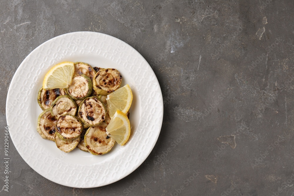 Wall mural tasty grilled courgette slices with lemon on grey textured table, top view. space for text