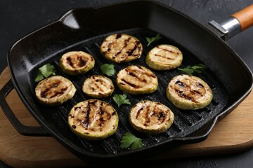 Tasty grilled zucchini slices with parsley in frying pan on grey table