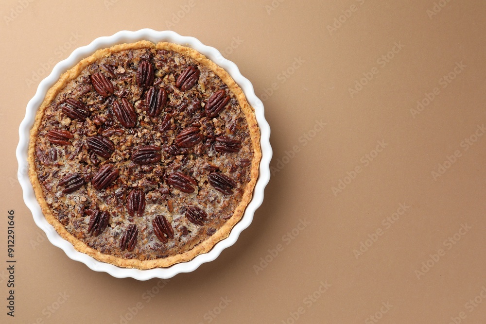 Wall mural delicious pecan pie in baking dish on light brown background, top view. space for text