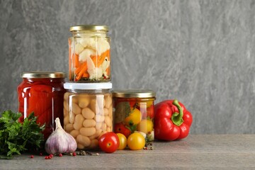 Different pickled products in jars on wooden table