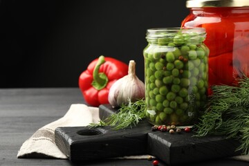 Different pickled products in jars and fresh ingredients on grey wooden table