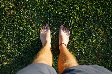 Man's feet on grass. Man practicing grounding or also called earthing