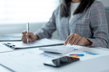 A woman is sitting at a desk with a calculator and a pen