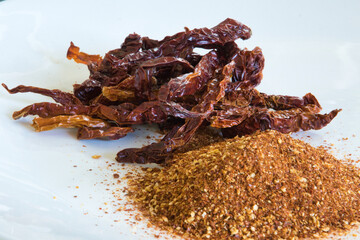 A pile of red chili peppers and a pile of red chili powder