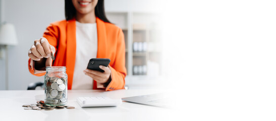 Saving money with hand putting coins in jug glass and calculator to calculate budget concept...