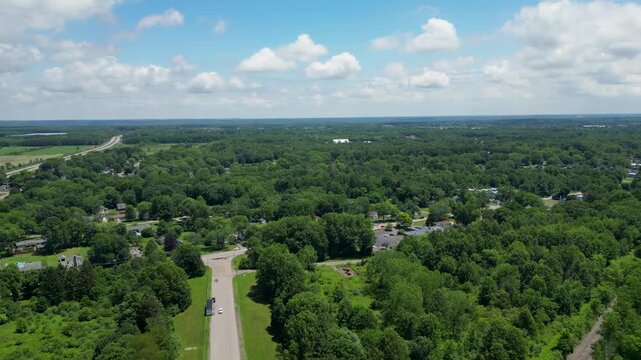 Stunning aerial footage of a vast green landscape with roads and scattered homes. Perfect for projects on nature, real estate, and urban planning. Highlights expansive greenery and open skies.