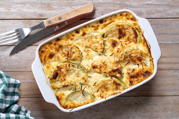 Casserole with cheese and gratin zucchini on wooden table. Top view