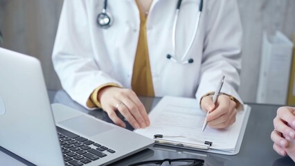 Doctor completing paperwork with patient. Close-up of a doctor's hands with forms, imparting information to a laptop. Medicine and health care concept