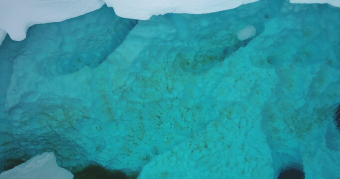 Crystal blue underwater Arctic iceberg melted ice. Snow cover glaciers melting in cold ocean water. Environment issue of global warming. Climate change concept ecology background. Aerial top down view