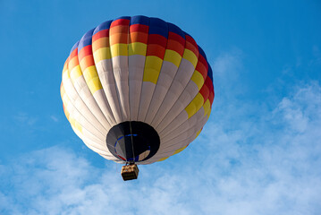 Fototapeta premium A colorful hot air balloon floating across the blue sky