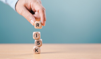 Risk management crisis concept. Financial analysis solution, real estate business. Businessman hand on economic risk word on wooden block, domino crisis. Insurance security assessment, blue background