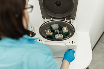 Scientist, worker, Laboratory technician using centrifuge device automation machine for testing and diagnostic clinical specimens sample in lab room of hospital. Medical science technology concept.