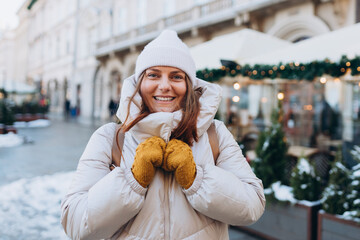 Happy 30s woman posing on urban background on winter snowy day. Winter holidays banner. Concept of vacations, holidays and happiness Christmas. High quality photo