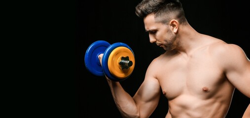 Male bodybuilder with dumbbell on dark background with space for text