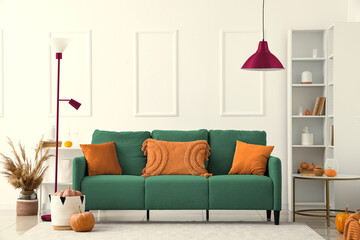Autumn interior of living room with cozy grey sofa, standard lamp and pumpkins