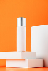 White sunscreen bottle with stylish props on orange background. Sunscreen concept. Skin care concept. Copy space.