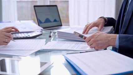 Business people wearing blue suits are reviewing financial data in office. Male auditor is using a magnifying glass. Audit and taxes concept
